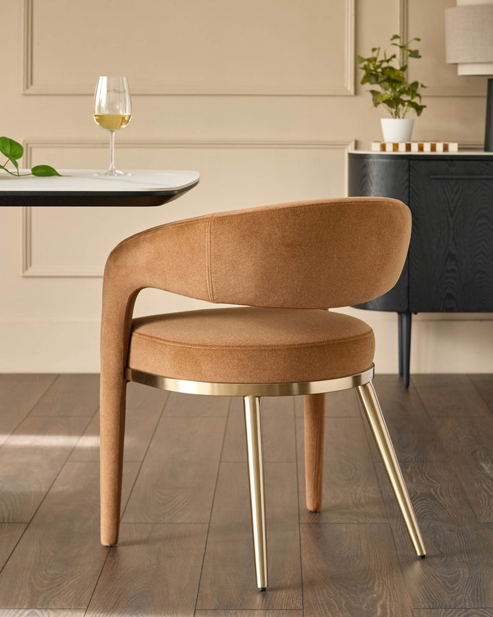Stylish tan chair with gold legs sits beside a modern table and dark wood sideboard, adding a touch of class to any dining space.