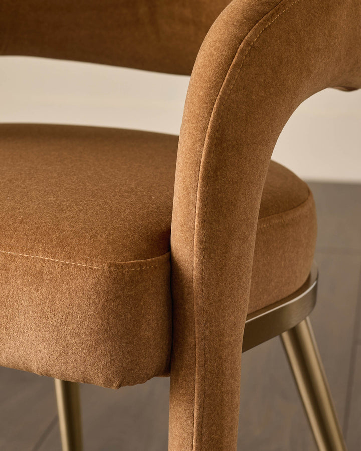 A stylish, brown, velvet chair with gold-coloured metal legs and armrests.
