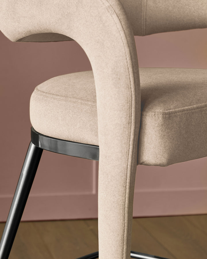 Champagne velvet bar stool with curved backrest and black metal legs, side view detail.