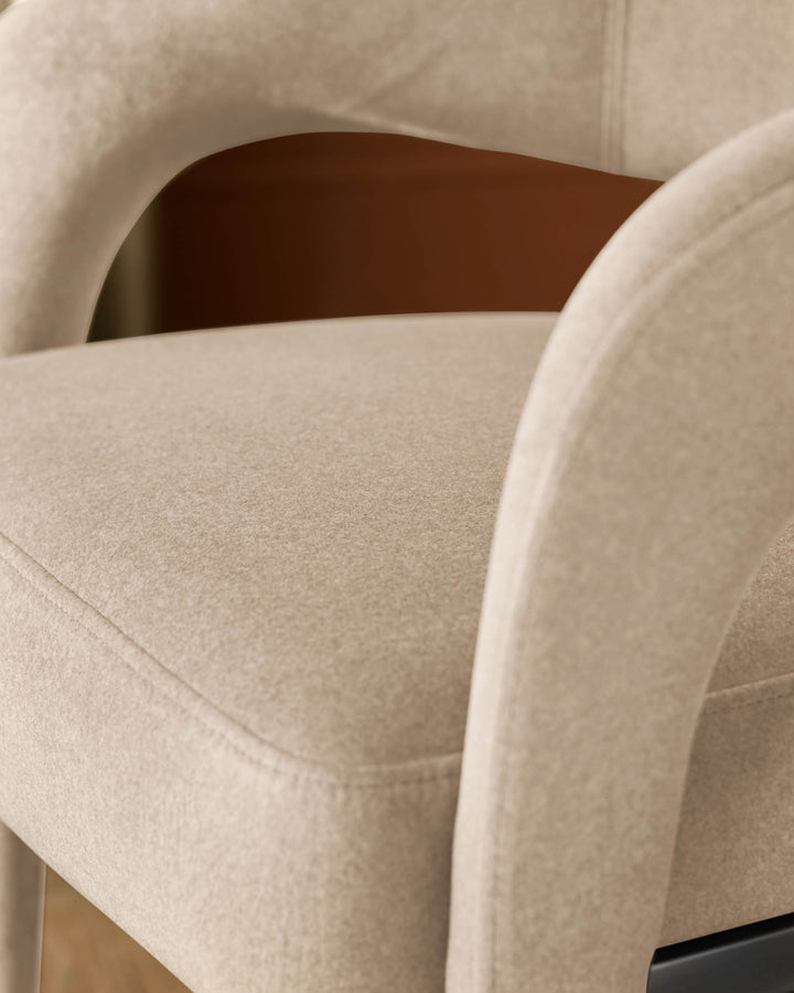 Rhett dining chair in champagne velvet, close-up detail of curved armrest and seat upholstery.