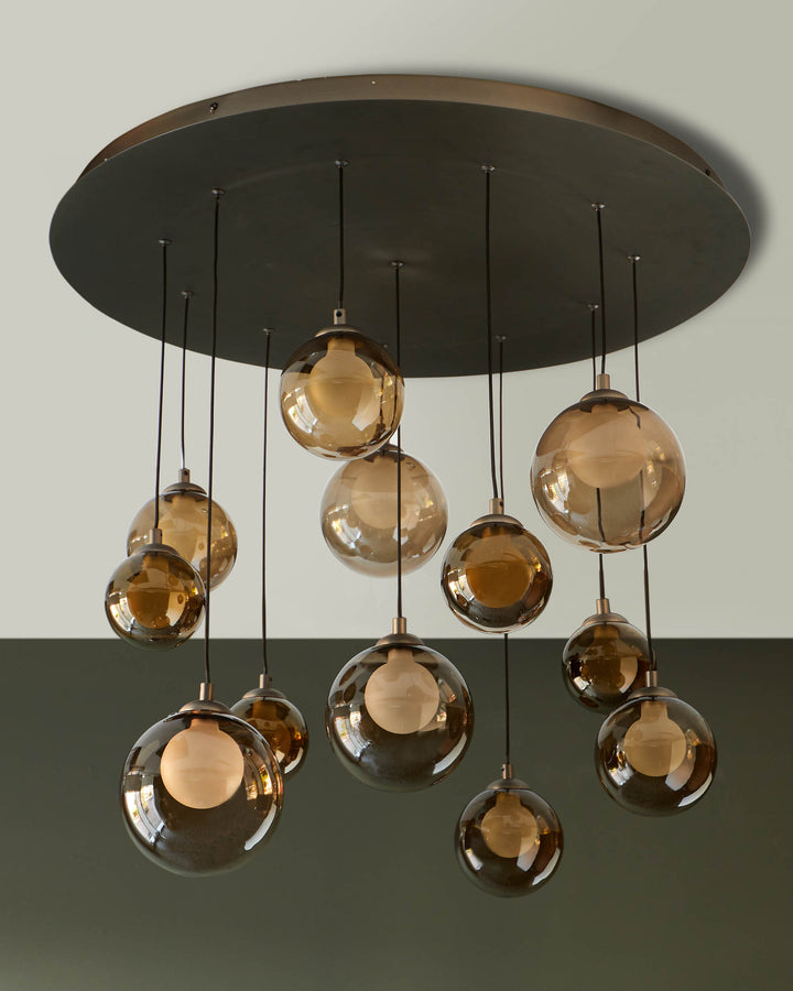 Stylish ceiling light fixture with multiple amber glass globes hanging from a circular bronze base. Modern lighting design.