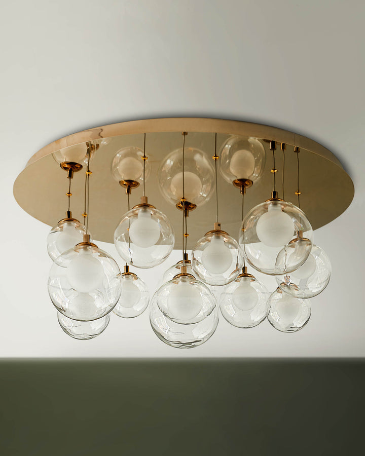 Contemporary ceiling light fixture with transparent glass globes and a gold coloured base plate.