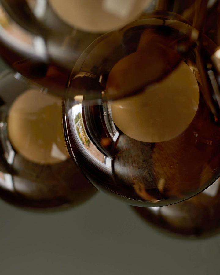 Glass bubble pendant lighting with brown-tinted glass and a light bulb visible through the glass, hanging from the ceiling.