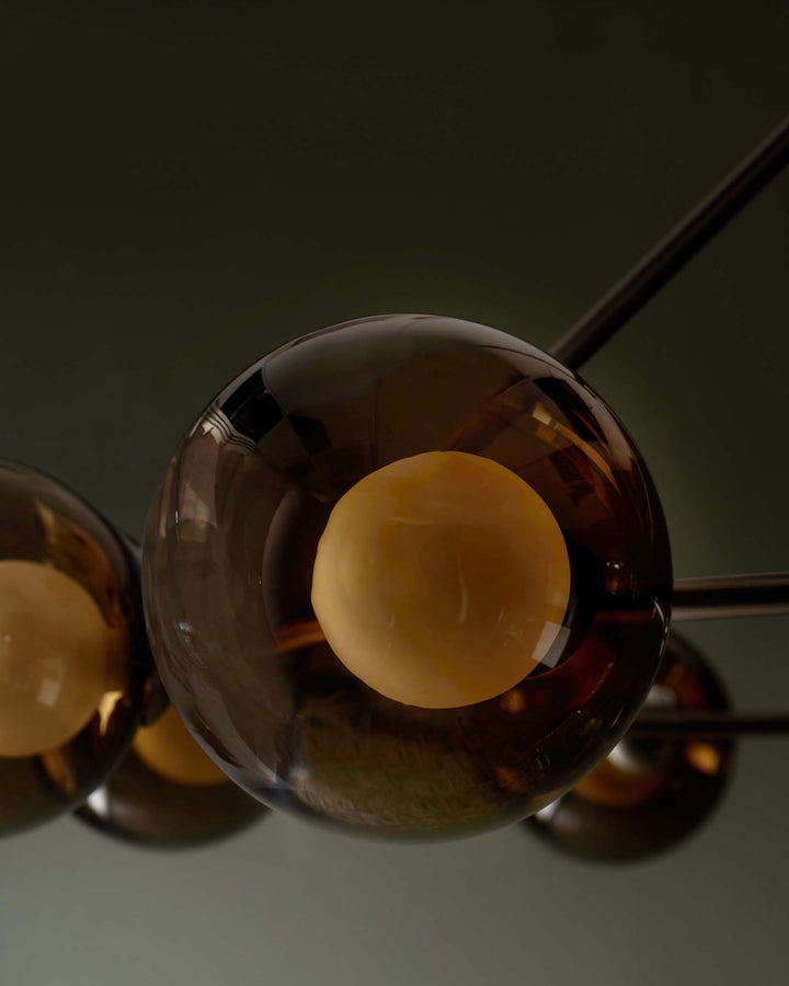 Close-up of a modern chandelier with smoked glass orbs and warm, inviting internal lights. Contemporary and stylish design.