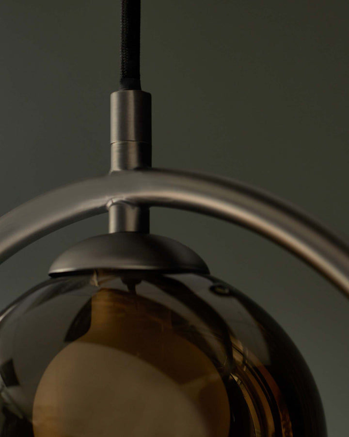 A modern hanging light fixture with a smoked glass globe and brushed metal frame provides a stylish illumination.