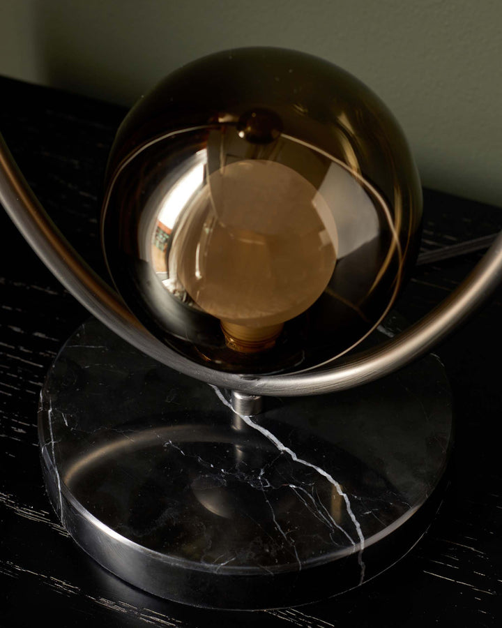 A lamp with a marble base, metal stand and smoked glass shade, showcasing a mid-century modern aesthetic.