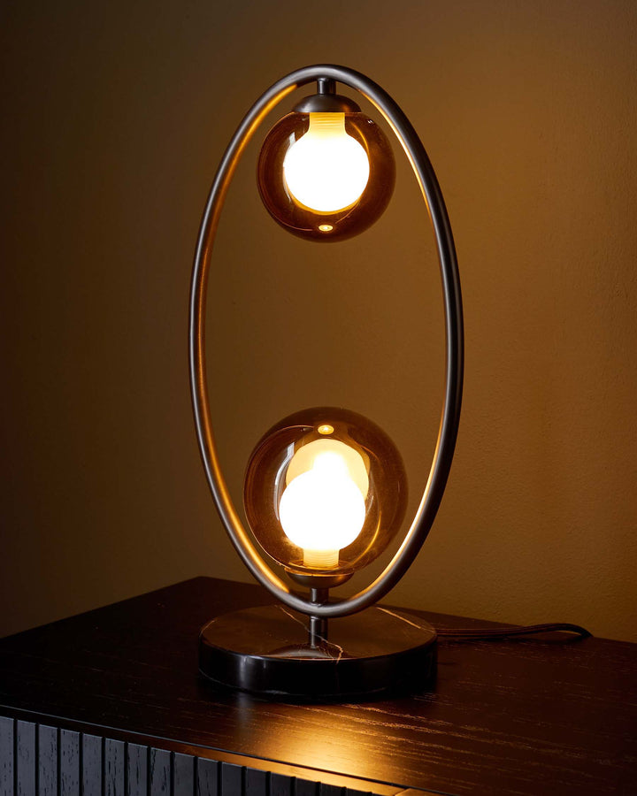 Stylish lamp with a metal frame and globe shades sitting on a dark wood cabinet, ideal for modern living spaces.