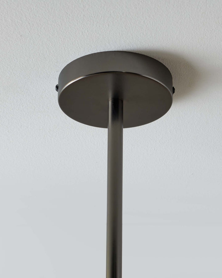 A sleek, dark metal pendant light fixture hangs from a white ceiling, showcasing modern design.