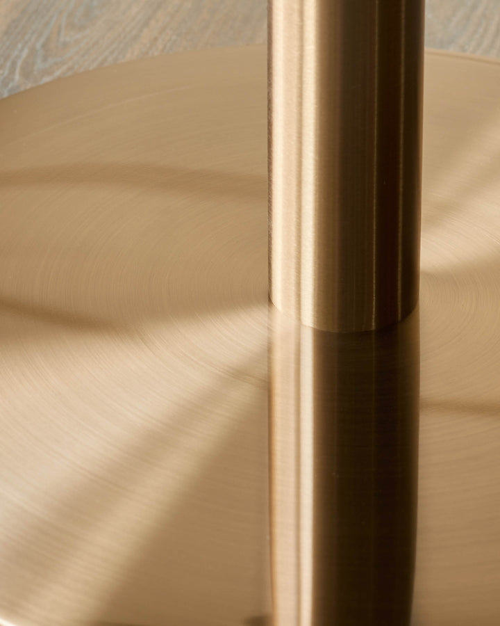 Close-up of a table base with a sleek, cylindrical support, finished in a warm, metallic tone.