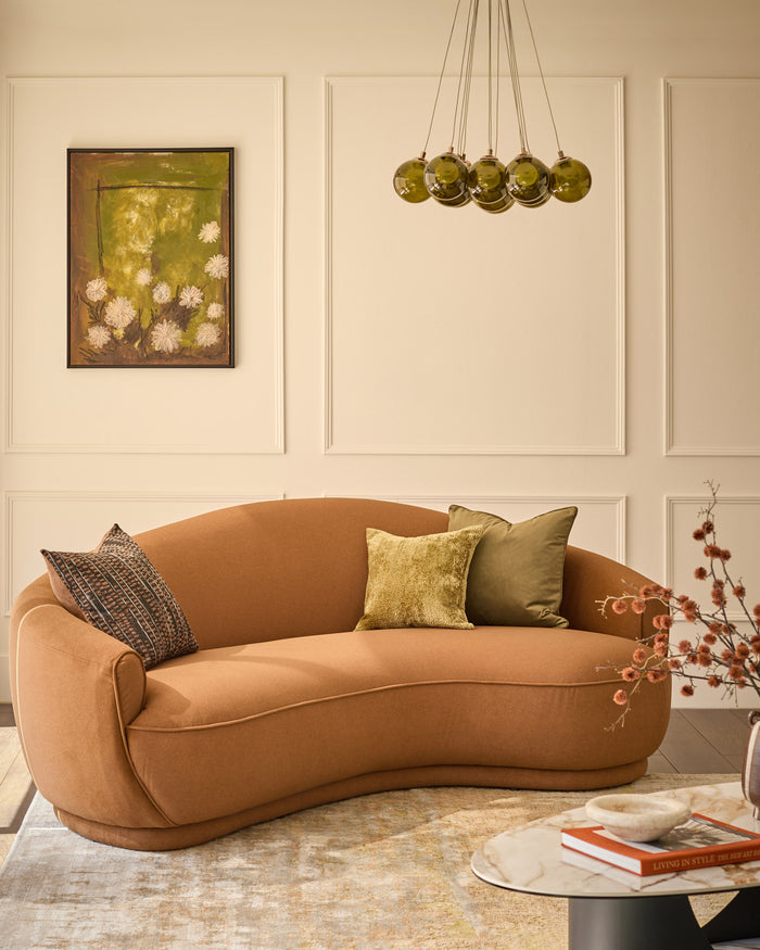 Rosetta 3-seater sofa in caramel fabric with curved shape, displayed in a styled living room setting with cushions and decor.
