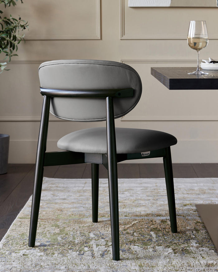 A stylish grey leather chair with dark wooden legs. Perfect for adding a touch of modern elegance to any dining space.