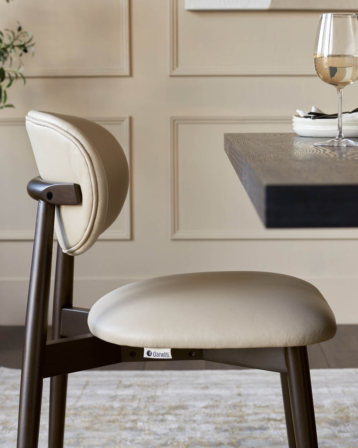 A stylish dining chair with a light beige leather seat and back, and a dark wood frame.