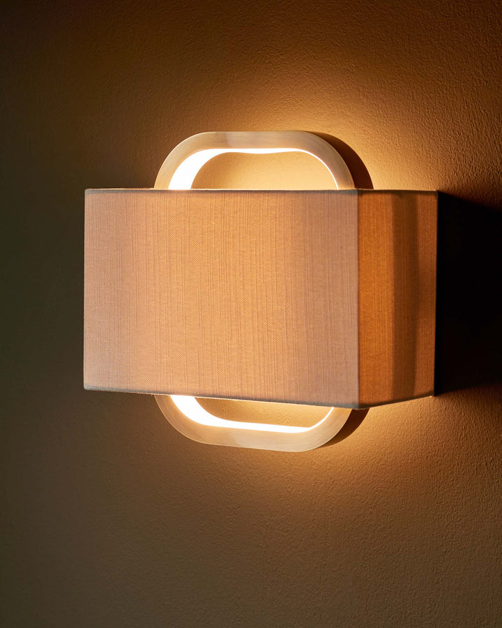 Modern wall light with a neutral shade and curved wooden frame, providing warm ambient lighting.