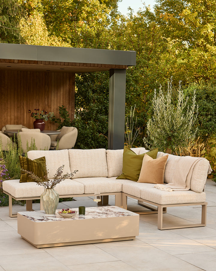 Savannah large corner garden sofa set in natural with beige cushions and matching coffee table in outdoor setting.