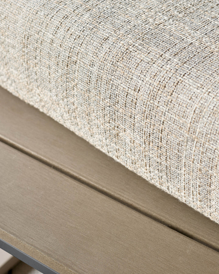 Cream upholstered corner bench with natural wood frame, close-up detail of woven fabric texture.