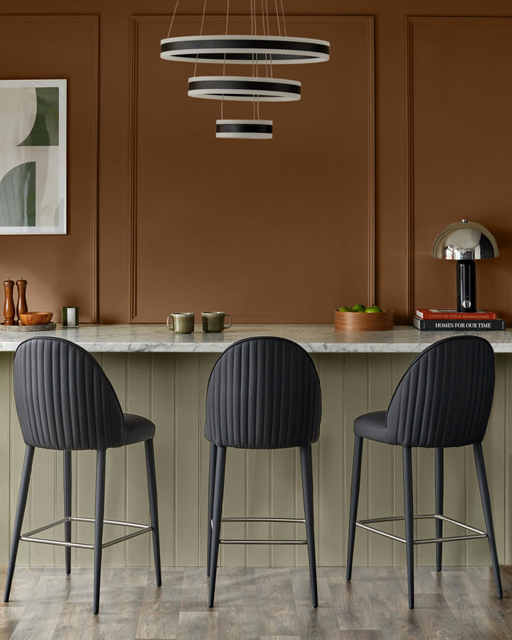 A kitchen counter with three black bar stools, above which hangs a striking, modern light fixture.