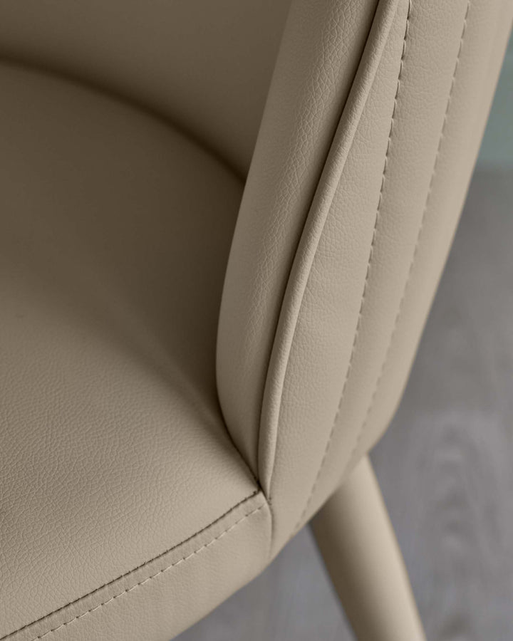 Close-up of a beige faux leather chair, showcasing the armrest and seat with detailed stitching.