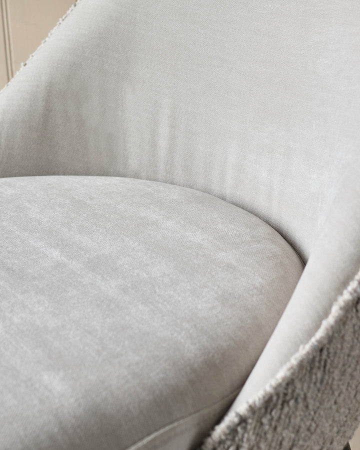 Close-up of a light grey upholstered chair, showing the seat and backrest. Soft, textured fabric for a cosy feel.