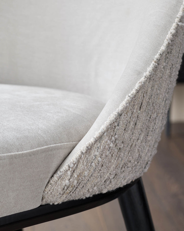 Close-up of a stylish chair with textured fabric and dark wooden legs, showcasing comfort and modern design.