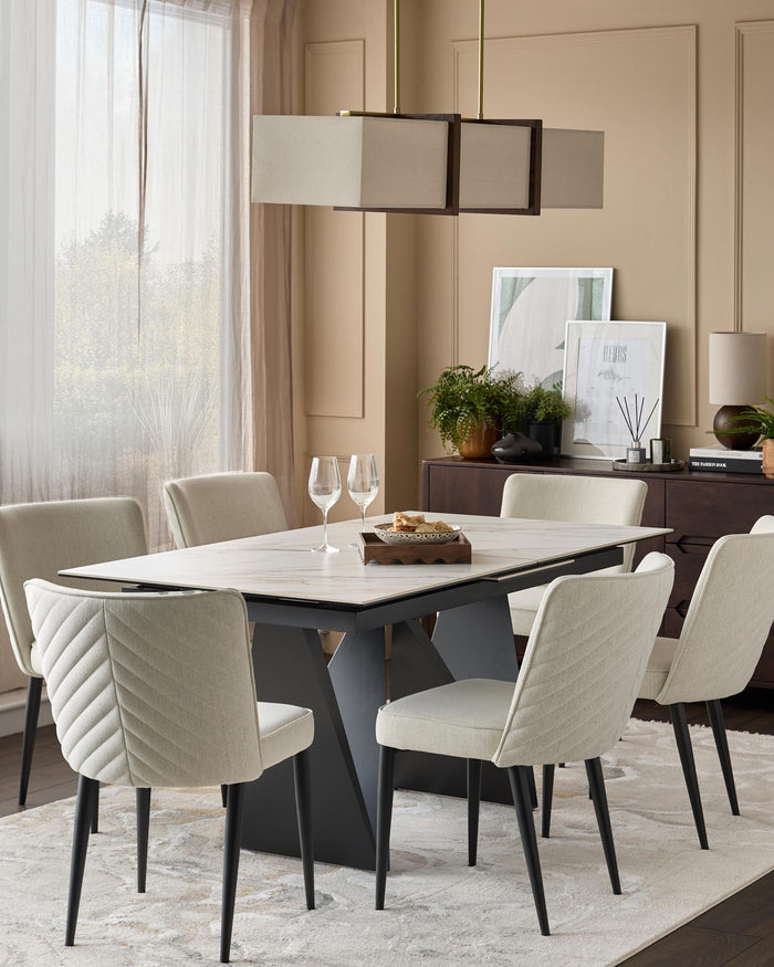 A modern dining set with light upholstered chairs, a marble-effect table and a stylish rectangular pendant light.