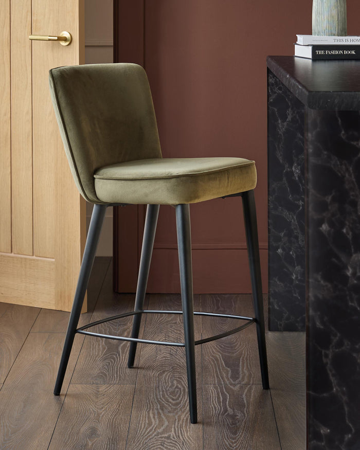 Stylish moss green bar stool with sleek black legs, perfectly complementing a modern kitchen or bar area.