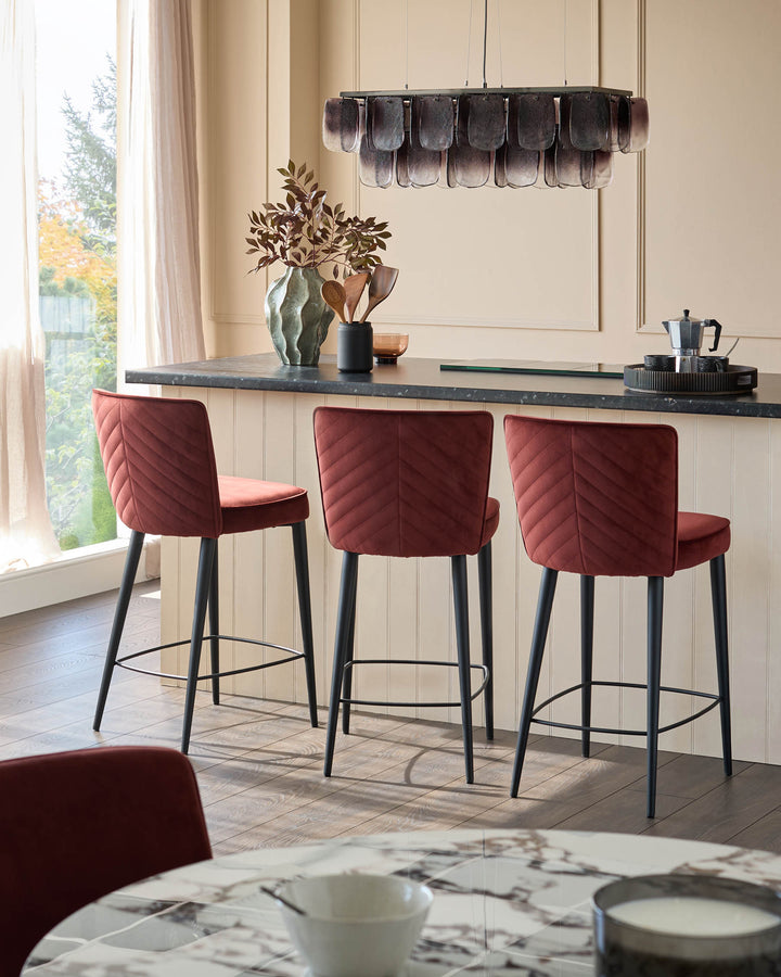 Kitchen island with three stylish red bar stools. Modern lighting and decor provide a contemporary touch.