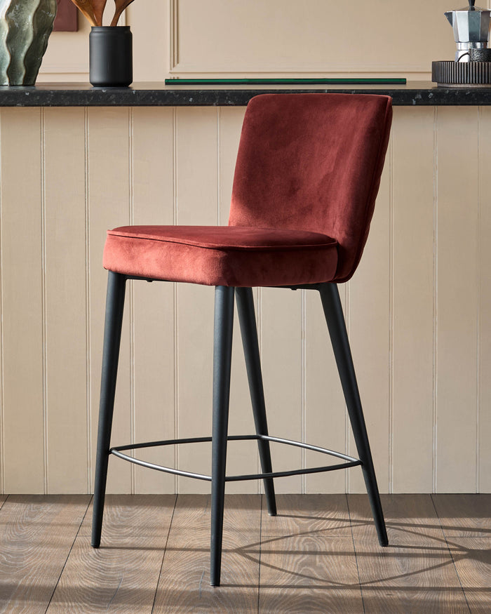 A stylish burgundy velvet bar stool with sleek black legs, perfect for adding a touch of luxury to your kitchen or bar area.