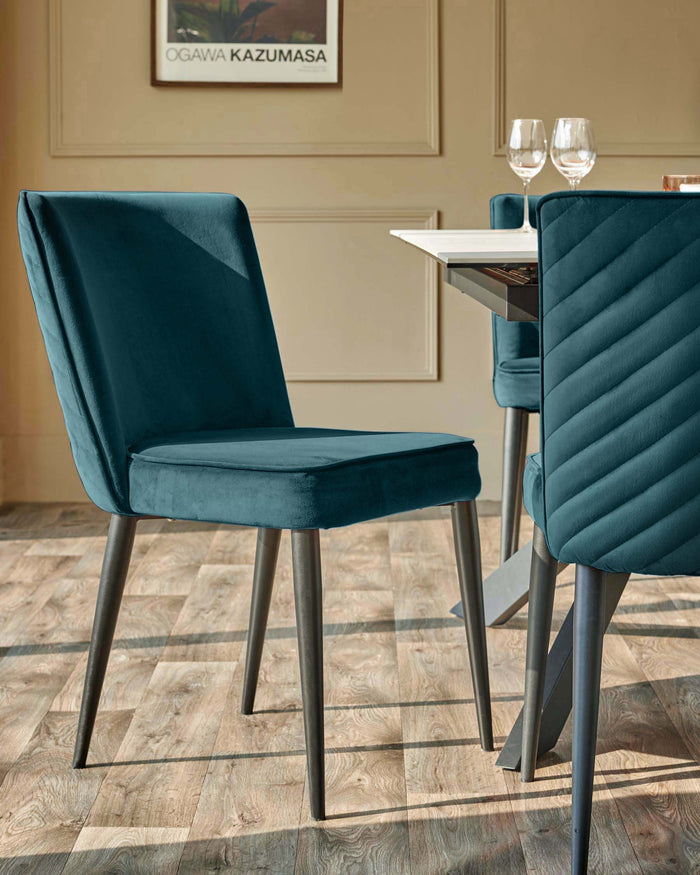 Stylish teal dining chairs with dark metal legs, paired with a modern white-topped table, create an inviting dining space.