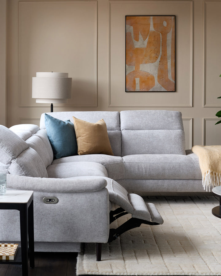Light grey chenille right-facing chaise recliner sofa with one seat reclined, shown in a styled living room setting.
