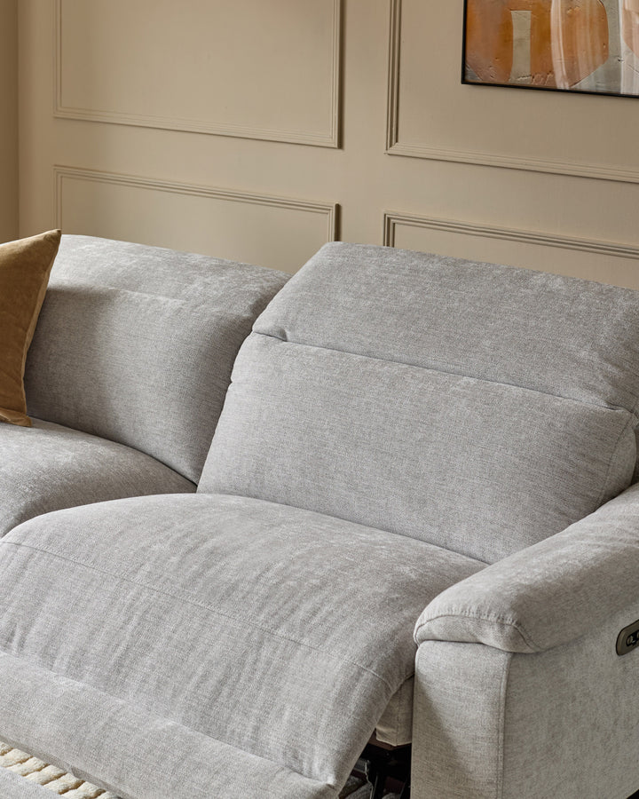 Serene 3-seater fabric recliner sofa in light grey with plush cushions and armrests, shown at an angle in a neutral interior.