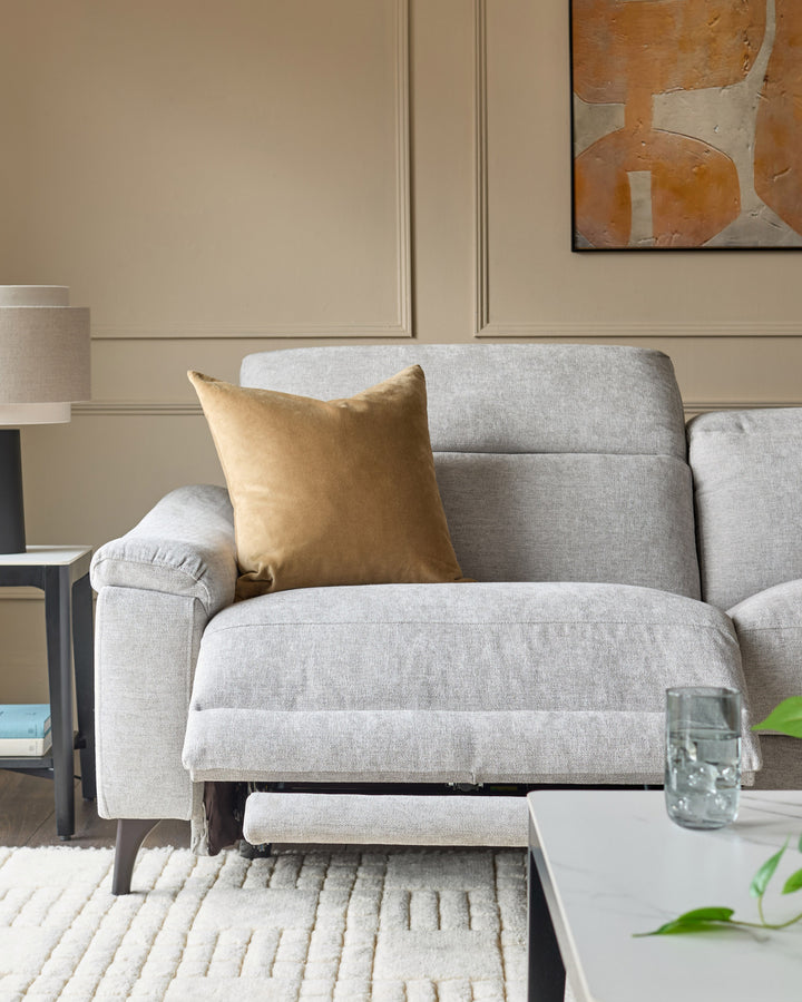 Serene 3-seater light grey fabric recliner sofa with footrest extended, styled with gold cushion in neutral living room.