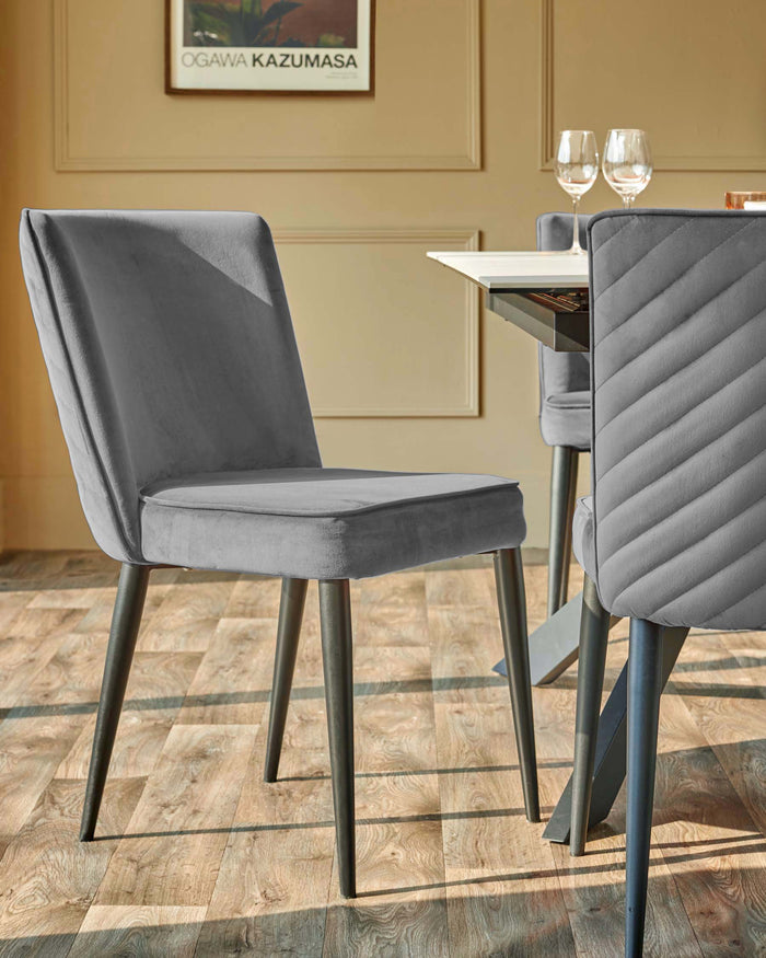 Grey upholstered dining chairs with dark metal legs sit around a modern dining table in a stylish dining space.