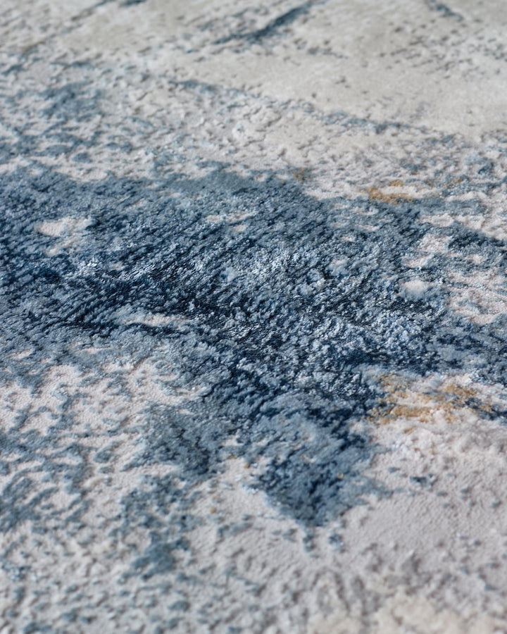 Close-up of a textured rug with abstract blue and beige patterns, perfect for adding warmth and style to any room.