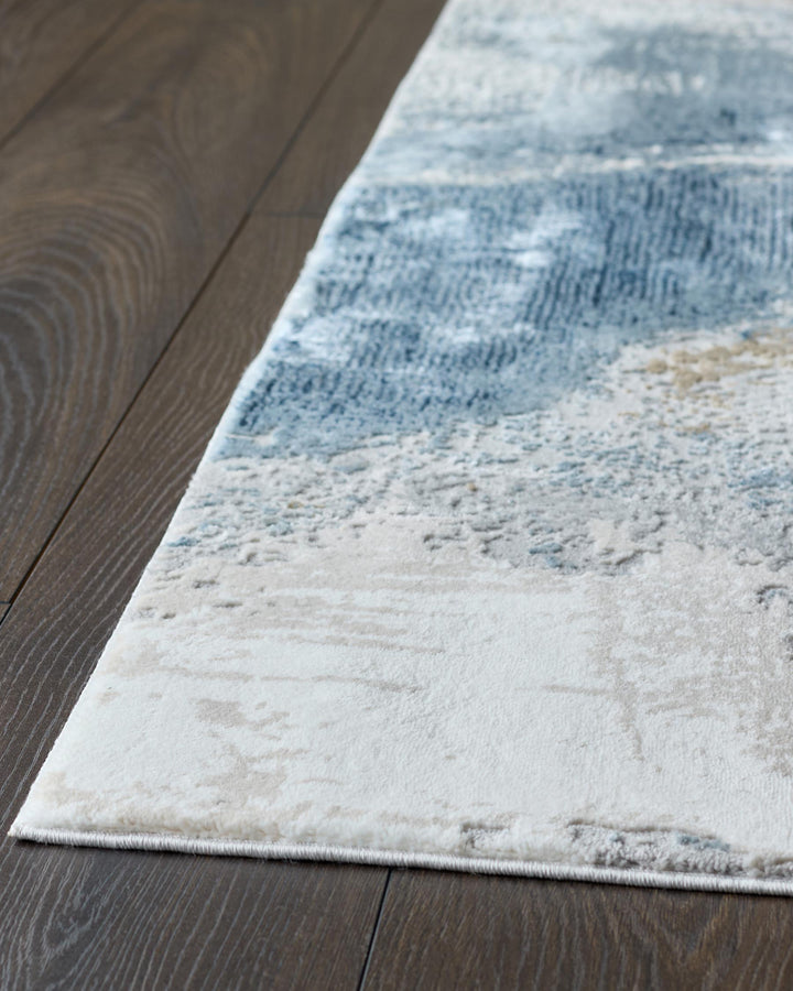 A contemporary rug with a marbled design, laid on a dark wooden floor.