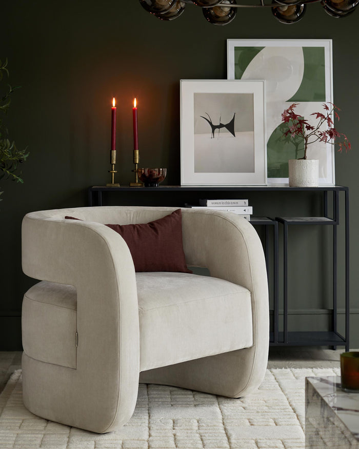 A modern armchair with a curved back, paired with a console table and art prints, creates a stylish living space.
