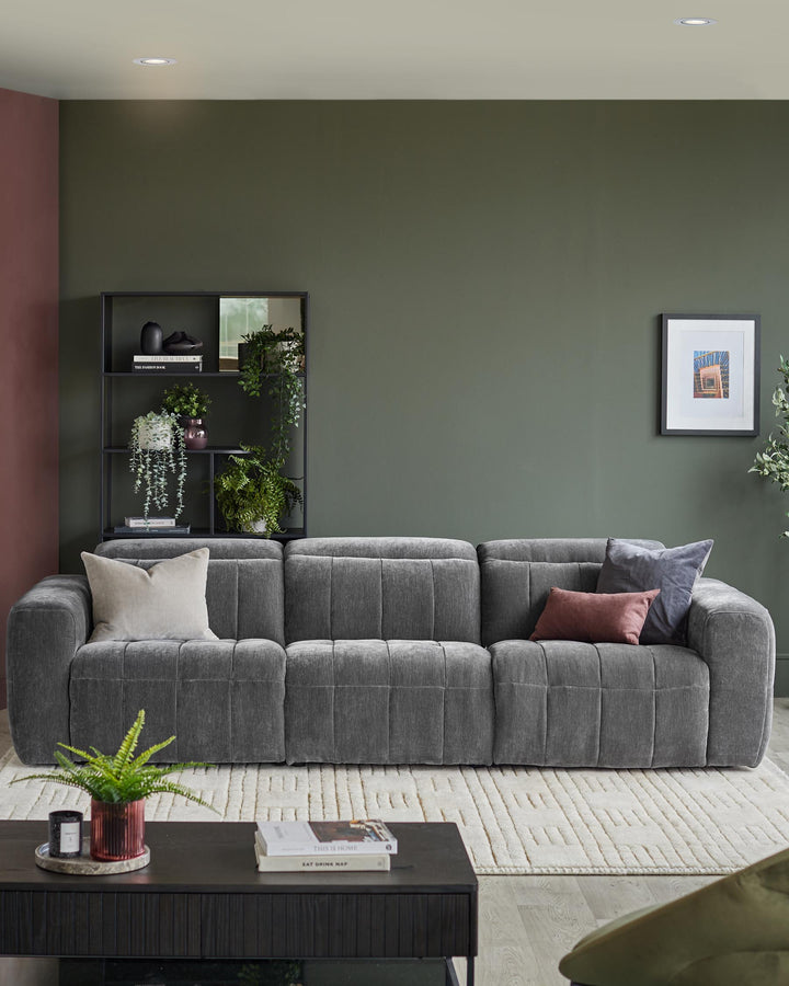 A modern grey sofa with plump cushions sits on a patterned rug, complemented by a dark wood coffee table and stylish shelving.