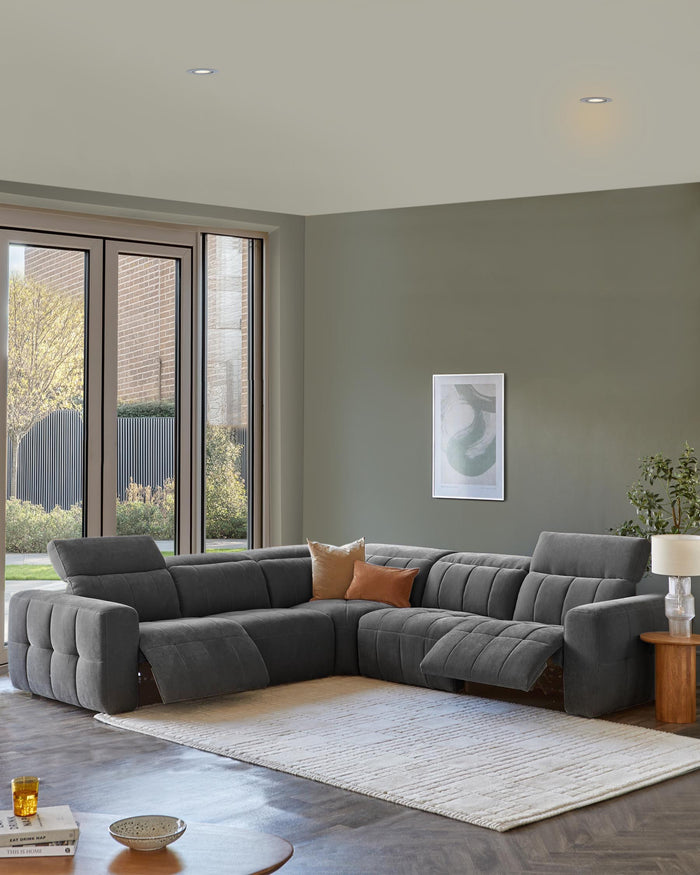 Modern gray sectional sofa with plush fabric, accented by decorative pillows, paired with a wooden side table and rug.