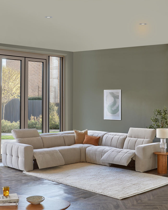 Modern L-shaped sectional sofa in light fabric with accent pillows, accompanied by a wooden side table and decorative rug.