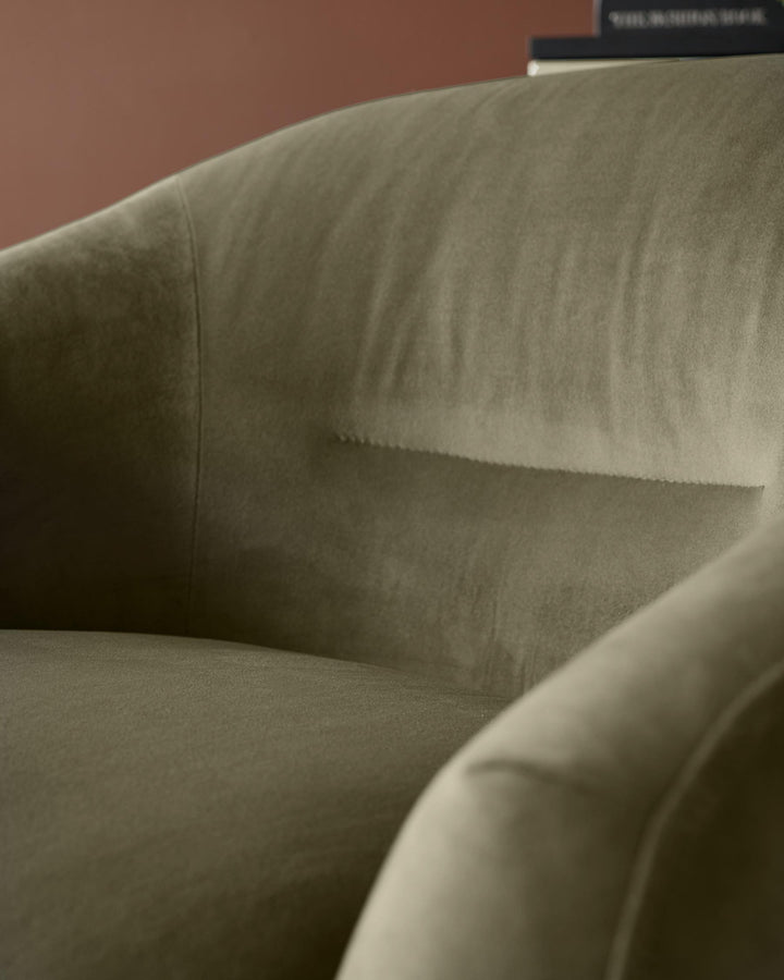 Close-up of a green velvet armchair, showcasing its soft texture and elegant design. Perfect for cosy living spaces.