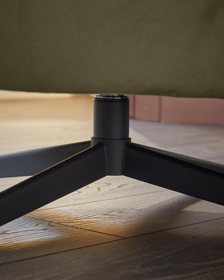 Close-up of a swivel chair's black metal base on a wooden floor, showcasing its modern design and sturdy construction.
