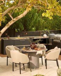 Tesso round dining table with four Camilo chairs in dark grey and natural, styled in outdoor patio setting.