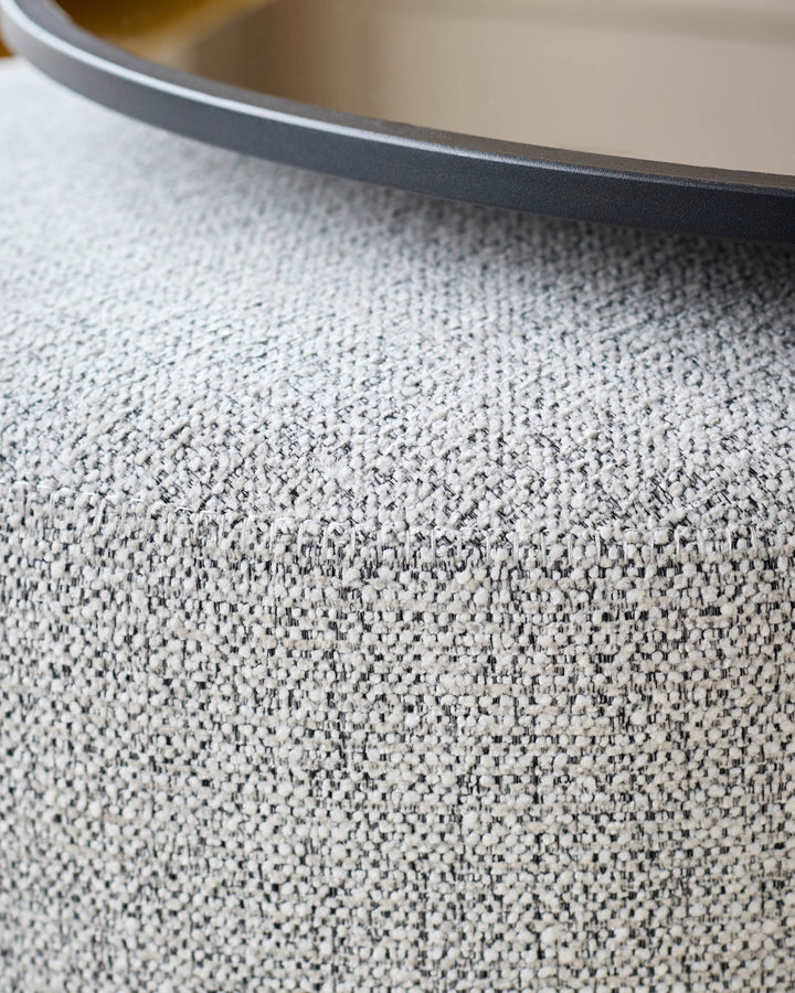 Close-up of grey textured fabric surface with black round table edge visible at top