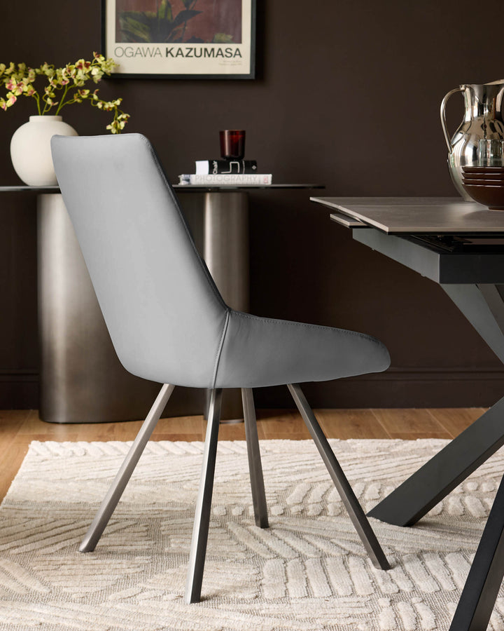 Theo mid-grey faux leather dining chair with tapered metal legs, shown in a modern dining room setting.