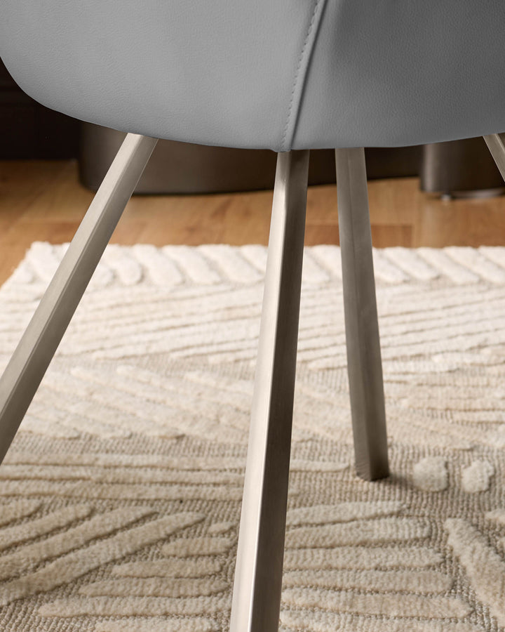 Theo mid-grey faux leather dining chair with angled tapered legs, shown from a low angle on a textured cream rug.