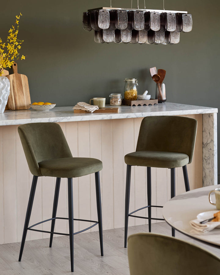Stylish kitchen featuring two olive-green bar stools with black legs, plus a round dining table with matching stools.