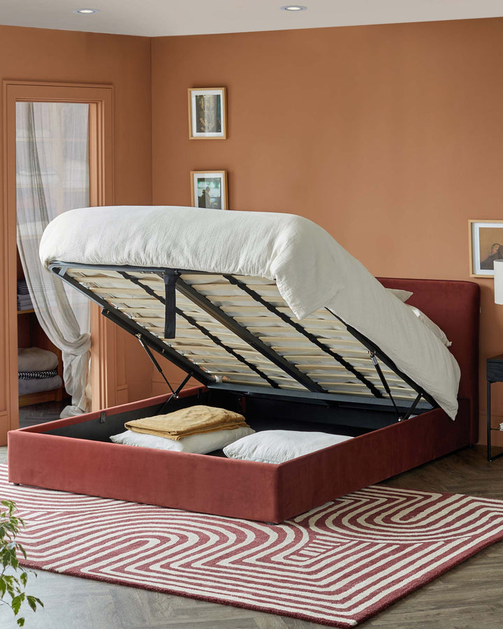Open storage bed frame with bedding, revealing storage space inside. Red and white rug on floor.