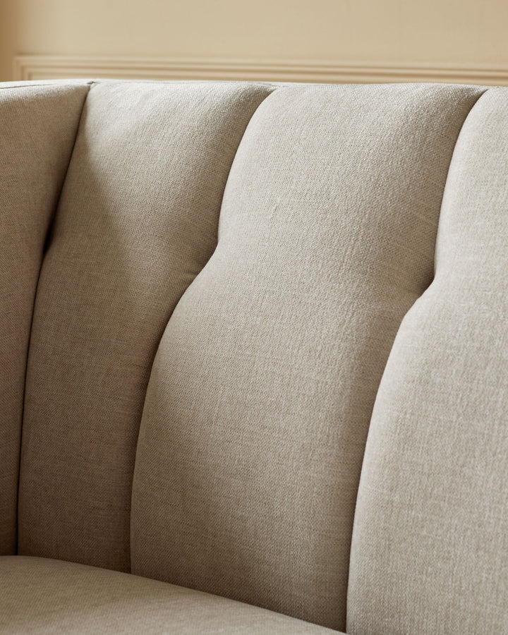 Close-up of the textured upholstery and curved back of a stylish, modern sofa in a neutral colour.