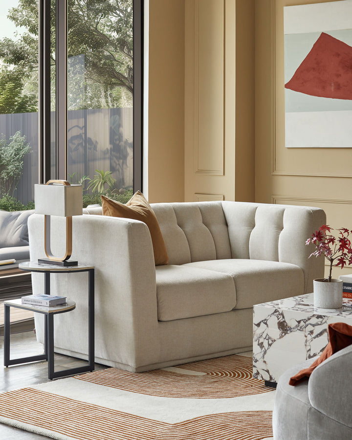 A contemporary lounge featuring a neutral sofa, marble coffee table and patterned rug, creating a stylish living space.