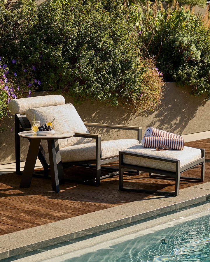 Bianco garden side table with black base and white Calacatta top, shown in poolside setting.