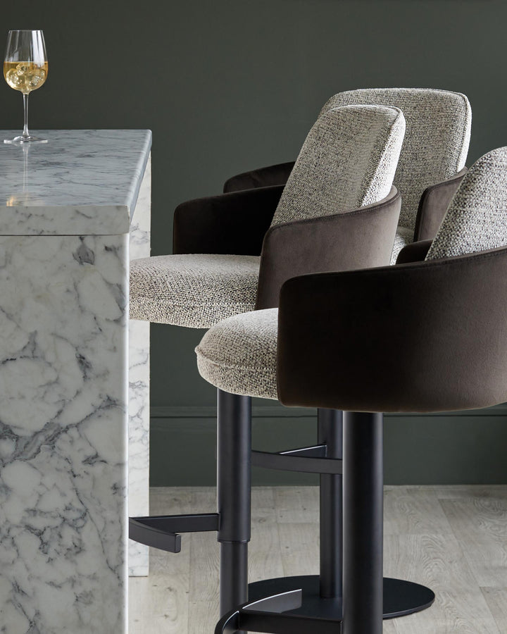 Stylish bar stools with dark arms and marble bar, plus a stemmed glass of white wine. Luxe and modern.